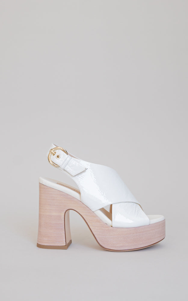 This 60's-inspired platform heel. Crossed straps in patent leather with a wooden platform.