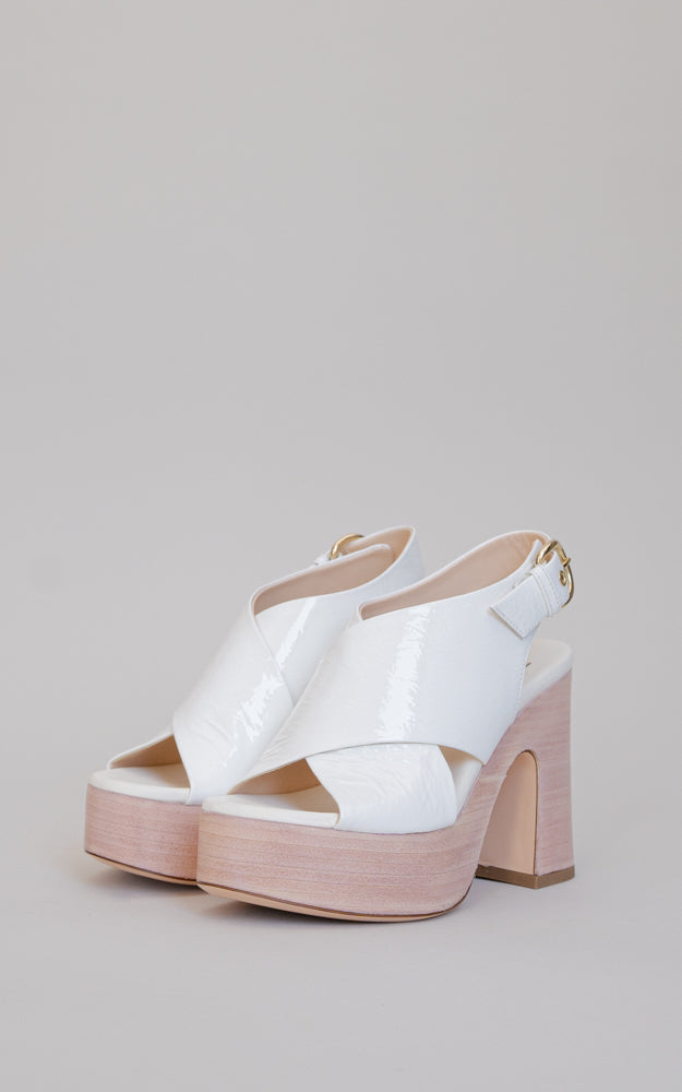 This 60's-inspired platform heel. Crossed straps in patent leather with a wooden platform.