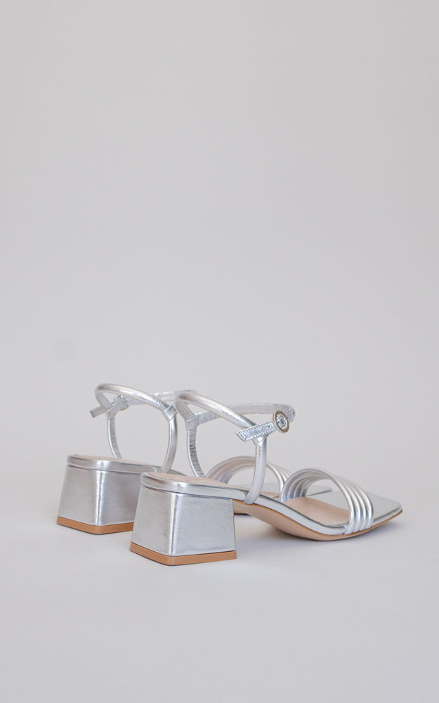 A dainty slingback. The Lena is a squared-toe sandal with four front straps, a rounded metallic buckle, standing on a 45mm block heel.
