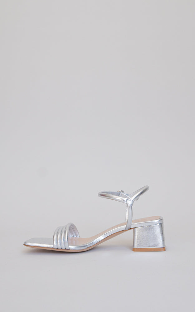 A dainty slingback. The Lena is a squared-toe sandal with four front straps, a rounded metallic buckle, standing on a 45mm block heel.