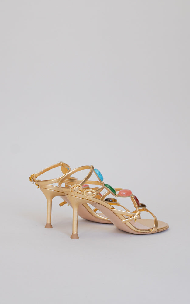 A gladiator sandal for the upcoming season. Standing on a 70mm stiletto heel, this round toe sandal has a gold ribbon buckle, and showcases the chakra-inspired natural cabochon stones. 
