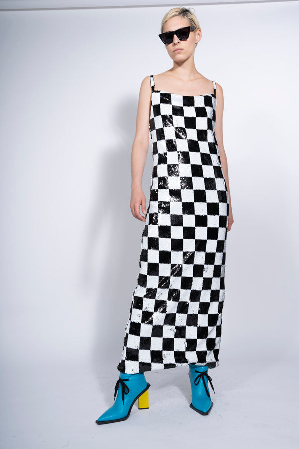 An 80's inspired dress. A Checkerboard sequins in black and white on this maxi dress with a square neckline and slit hem.